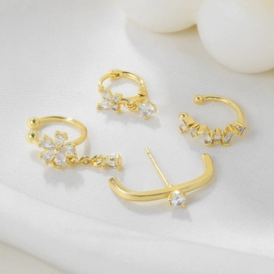 Detail of 18k gold plated flower earrings with sparkling cubic zirconia on white silk