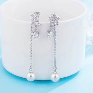 Macro shot of silver crescent moon and star tassel earrings with white pearls