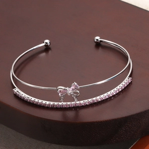 Macro view of silver bow bangle with double-layer band and sparkling pink zircon stones