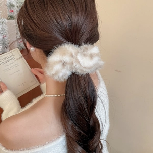 Elegante elastico per capelli in finta pelliccia beige indossato su una coda di cavallo
