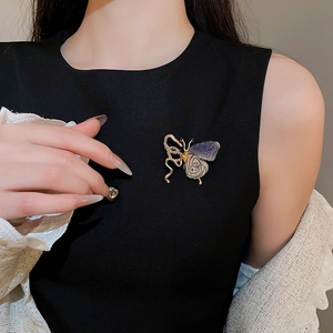 Detailed view of a vintage gold butterfly brooch with purple enamel on a black garment