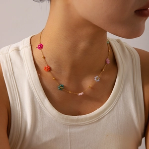 Close-up of a 18K gold stainless steel necklace with colorful beaded flower charms on model