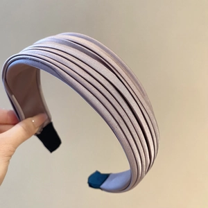 Gros plan sur un serre-tête en satin lilas plissé avec texture douce et design large