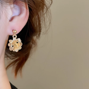 Close-up of elegant gold flower stud earrings with detailed petal texture on model's ear
