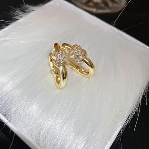 Detail of gold C-shaped hoop earrings with sparkling zircon star pattern on white faux fur