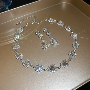 Detailed view of silver-tone teardrop crystal necklace and earrings on a gold tray