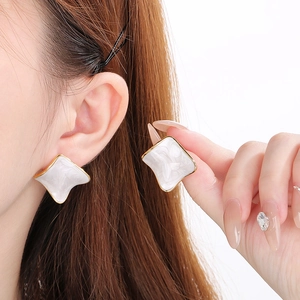 Detail view of square gold earrings featuring elegant white marble resin inlay for women