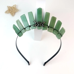 Close-up of green crystal crown with silver moon and star charms on a black headband