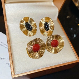 Details von Vintage-Goldohrringen mit Reliefmustern und schwarzen sowie roten Einlagen