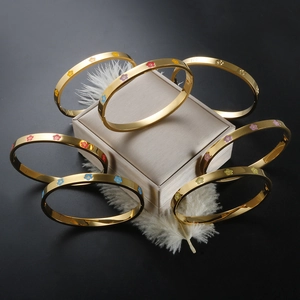 Close-up of golden enamel plum blossom bracelets with heart detail on a white feather