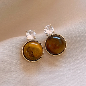 Macro shot of resin tiger eye leopard print earrings with silver pins on soft fabric