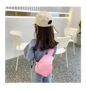 Back view of a child wearing a pink cylindrical crossbody bag with adjustable strap