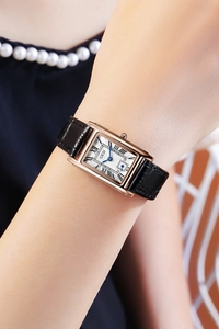 Wrist shot of rectangular rose gold quartz watch with black leather strap and blue hands