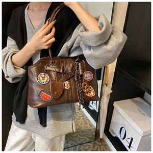 Vue détaillée du sac vintage marron avec des écussons brodés décoratifs et des badges