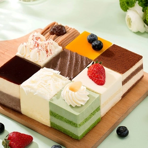 Detailopname van moussegebakjes in diverse smaken op houten plank met vers fruit erop