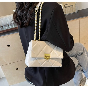 Close-up of ivory quilted handbag with golden twist lock and leather chain strap