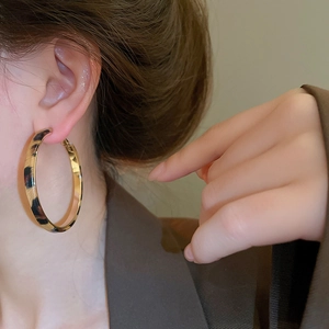 Close-up of leopard print large hoop earrings on a model for a stylish fashion look