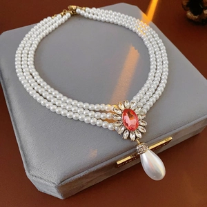 Détail du collier de perles à trois rangs avec gemme pêche et pendentif en perle
