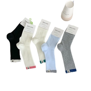 Five pairs of Japanese-style cotton crew socks in assorted colors with logo labels