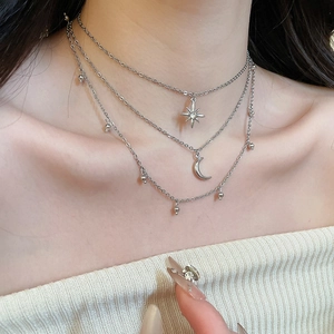 Detail of a three-layer silver necklace with rhinestone star and moon pendants on neck