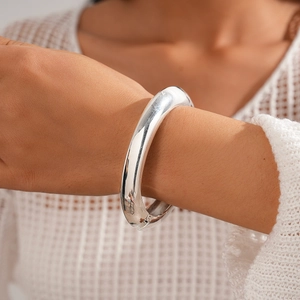 Close-up of a minimalist silver chunky bangle with mirror-polished finish and hinge detail