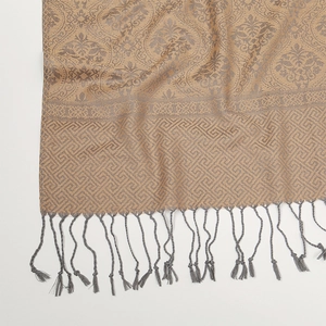 Dettaglio macro sciarpa jacquard oro con motivi paisley grigi e bordi a frange