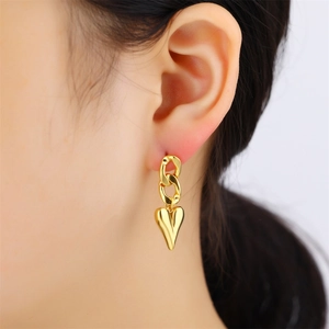 Close-up of golden heart drop earrings with chain links on model for an elegant look