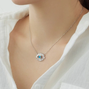 Detail of S925 sterling silver evil eye necklace with blue gem on model neck