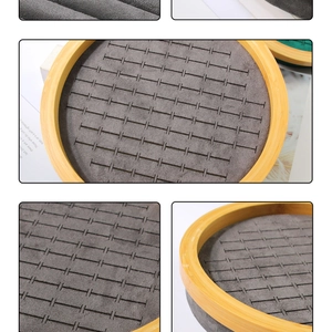Macro view of a round bamboo jewelry tray with grey velvet slots for rings and studs