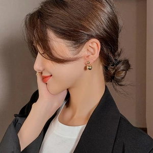 Minimalist gold double ball geometric stud earrings worn by a model in a side view