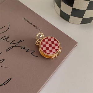 Detail of a small gold alloy hair claw featuring a red and white checkered pattern inlay