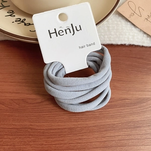 Close-up of grey elastic hair bands on wood surface with fabric texture detail