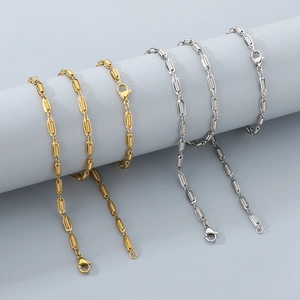 Detail of ribbed oval links on gold and silver chain necklaces draped over grey display