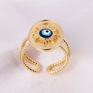 Macro detail of golden Evil Eye ring with sunburst texture on purple satin background