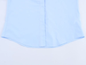 Detailaufnahme des hellblauen Popeline-Hemdes mit geschwungenem Saum und präzisen Nähten