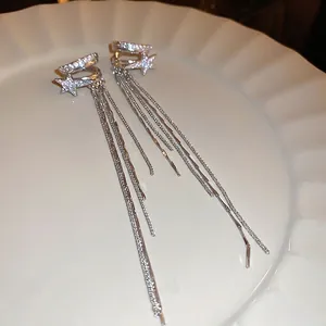 Orecchini a stella d'argento con nappe di zirconi su vassoio di ceramica bianca chic