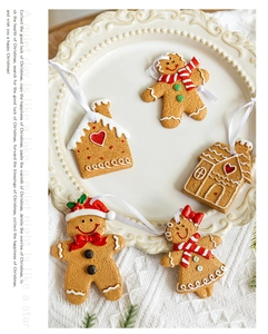 Detail of five gingerbread man and house ornaments on a white ceramic plate with soft lighting