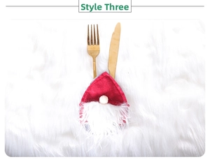 Detail of red gnome Christmas cutlery holder with golden knife and fork on white fur