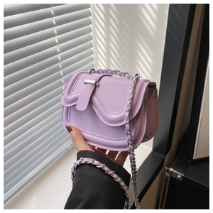 Detail shot of a purple mini saddle bag with silver chain strap held in hand