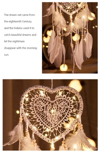 Detail of white heart dreamcatcher with lace, soft feathers, beads and warm LED lights