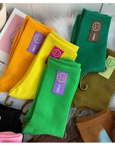 Détail de chaussettes en maille colorées avec patch sourire sur tapis en fausse fourrure