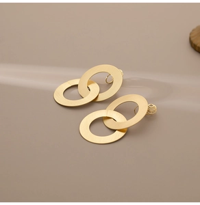 Vue macro de boucles d'oreilles doubles anneaux dorés mats avec texture en métal brossé
