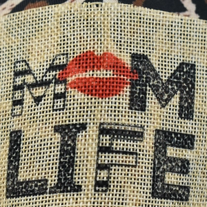 Close-up of MOM LIFE text and red lip print on leopard ponytail baseball cap fabric
