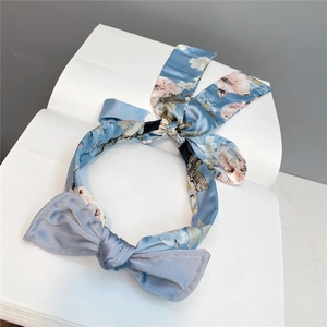 Close-up of sky blue floral satin headband with large bow and elegant long ribbons