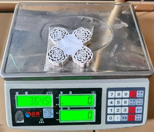 Detailed view of hollow birdcage lace paper candy boxes being weighed on an industrial scale