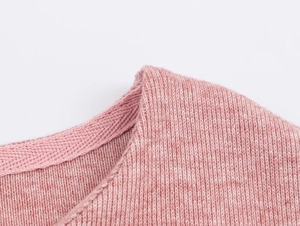 Vue macro de l'encolure et des coutures d'épaule d'un ensemble jupe en tricot rose