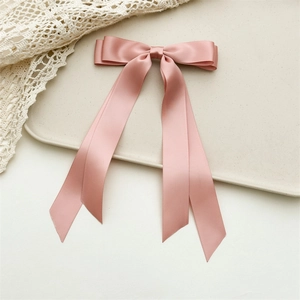 Detail view of pink satin double bow hairclip with long ribbons on a lace background