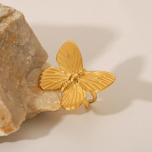 Minimalist gold butterfly open ring made of polished stainless steel on a stone pedestal