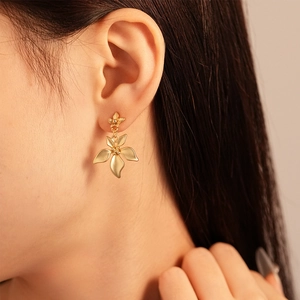 Close-up of elegant gold double-layered flower petal earrings worn by a female model