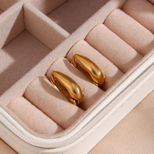Polished 18K gold-plated stainless steel teardrop hoop earrings on pink velvet